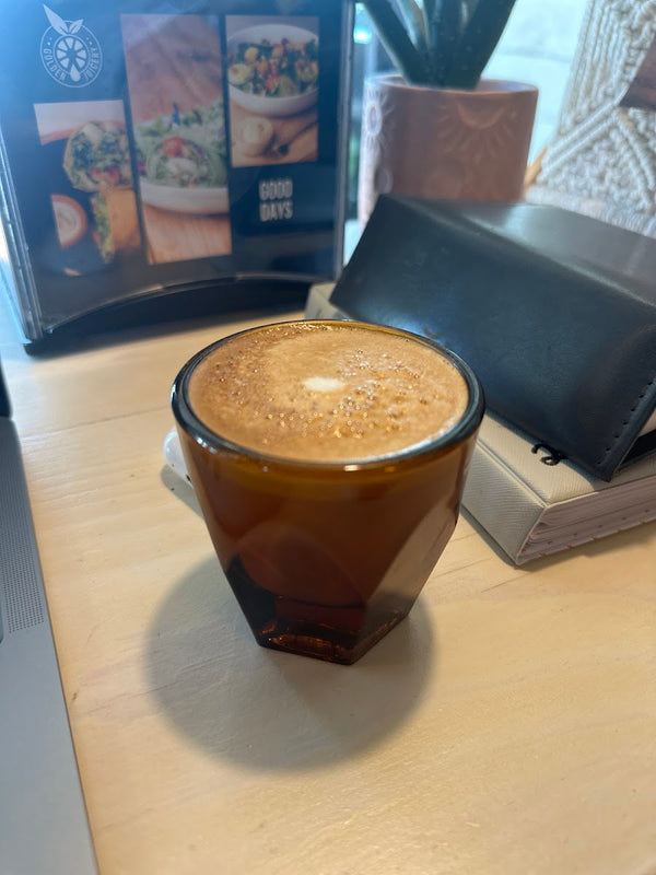 Cortado in a Golden Juicery glass with menu in background at Golden Juicery Jupiter