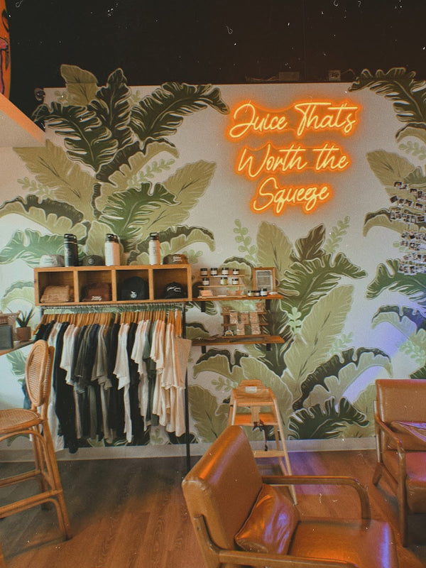 Juice That's Worth the Squeeze neon sign and merch wall at Golden Juicery Jupiter